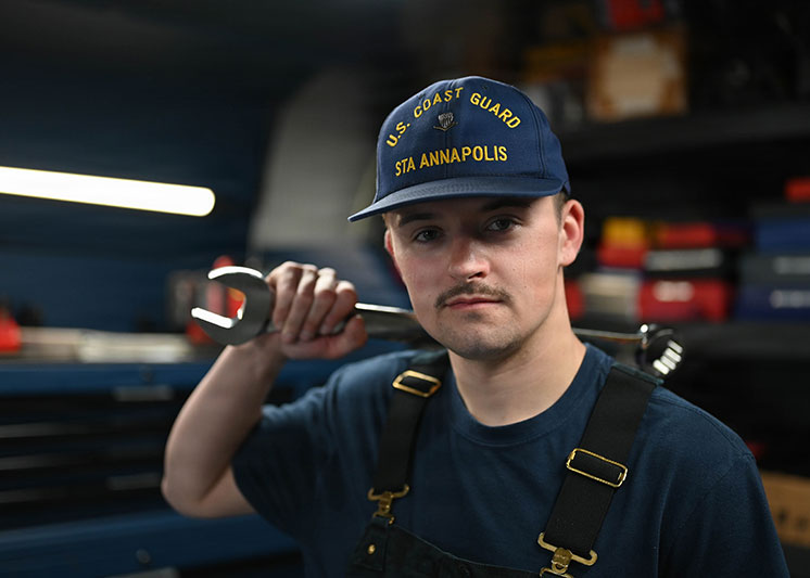 A coastie holding a wrench. Links to Donor-Advised Funds